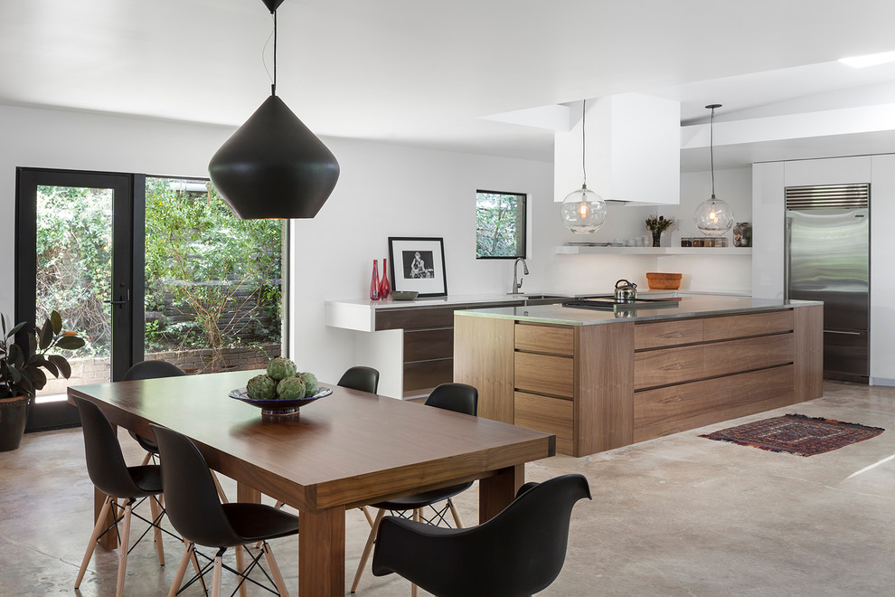 Photo of a contemporary galley eat-in kitchen in Austin with a farmhouse sink, flat-panel cabinets, medium wood cabinets, stainless steel appliances, concrete floors and with island.