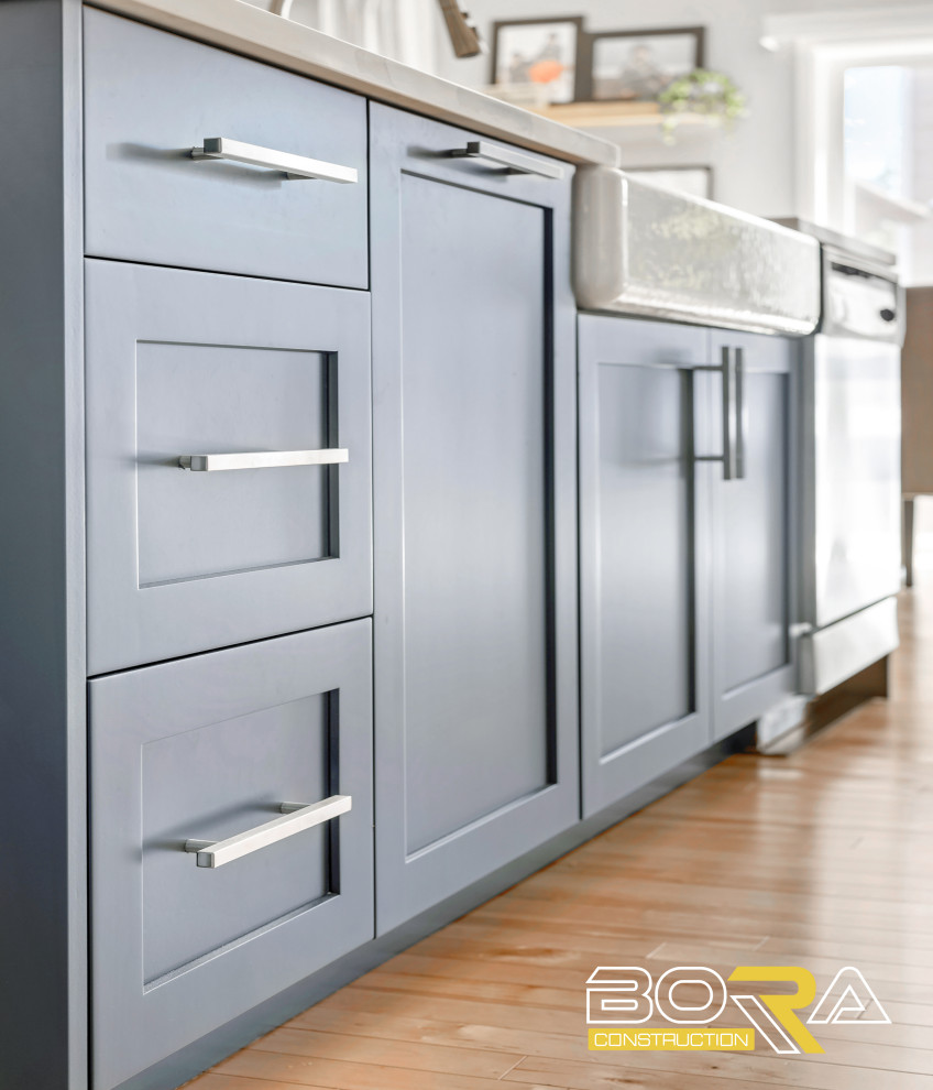 Inspiration for a mid-sized single-wall light wood floor and brown floor eat-in kitchen remodel in Seattle with a farmhouse sink, shaker cabinets, white cabinets, quartz countertops, white backsplash, quartz backsplash, stainless steel appliances, an island and white countertops