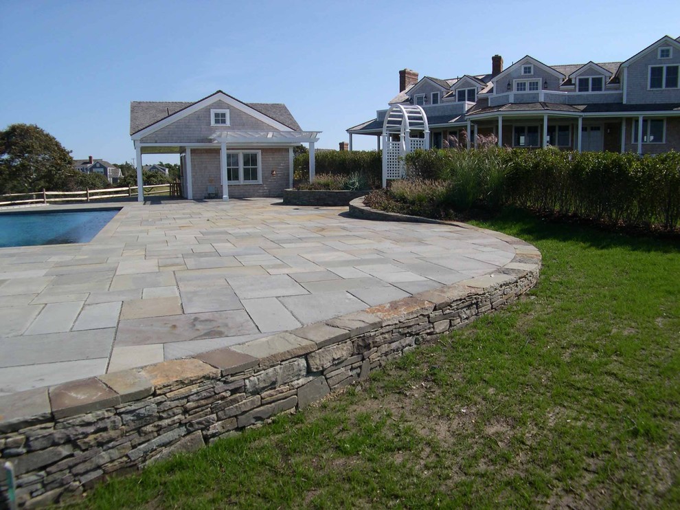 This is an example of a large traditional backyard rectangular natural pool in Boston with a hot tub and natural stone pavers.