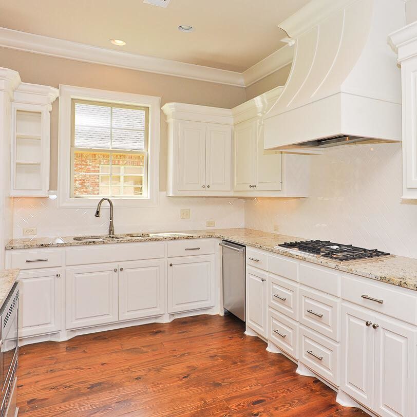 Inspiration for a mid-sized transitional l-shaped dark wood floor and brown floor open concept kitchen remodel in Jackson with a double-bowl sink, raised-panel cabinets, white cabinets, granite countertops, white backsplash, ceramic backsplash, stainless steel appliances and an island