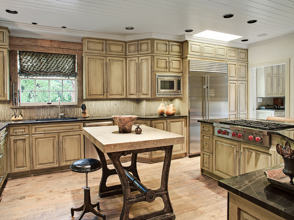 Inspiration for a traditional separate kitchen in Austin with an undermount sink, raised-panel cabinets, distressed cabinets, beige splashback, stainless steel appliances, light hardwood floors and with island.