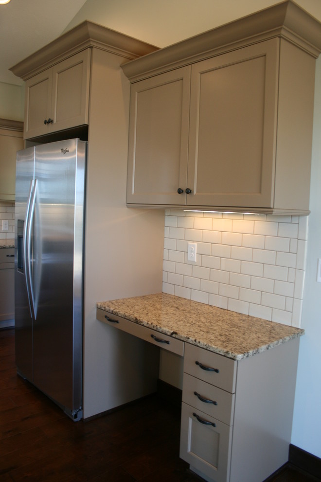 Inspiration for a mid-sized rustic dark wood floor kitchen remodel in Omaha with an undermount sink, shaker cabinets, beige cabinets, granite countertops, white backsplash, subway tile backsplash, stainless steel appliances and an island