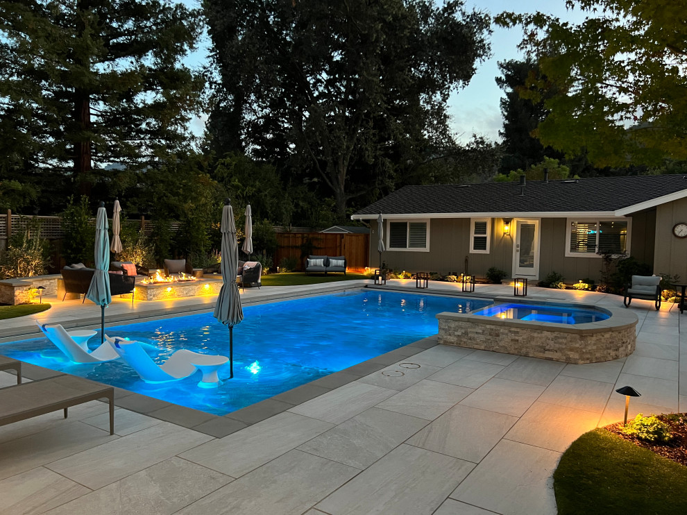 Ejemplo de piscina alargada de estilo americano grande rectangular en patio trasero con privacidad y suelo de baldosas