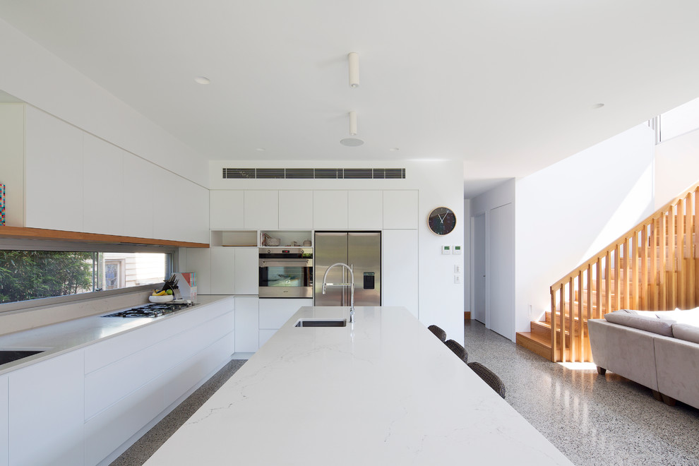 Inspiration for a large contemporary l-shaped open plan kitchen in Sydney with a double-bowl sink, flat-panel cabinets, white cabinets, solid surface benchtops, stainless steel appliances, concrete floors and with island.