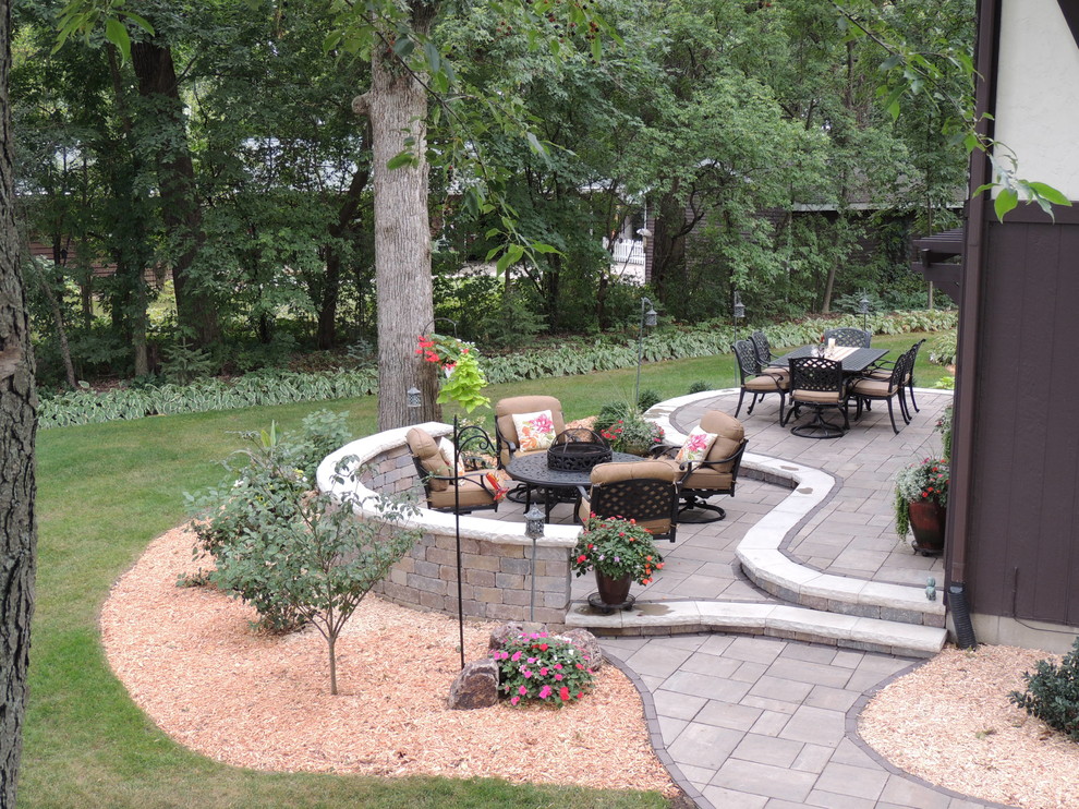 This is an example of a large country backyard patio in Other with a fire feature, natural stone pavers and no cover.