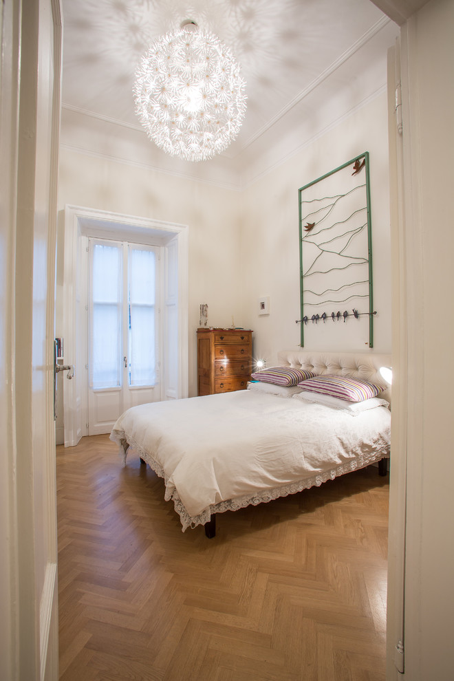 Design ideas for a mid-sized traditional master bedroom in Milan with white walls and light hardwood floors.