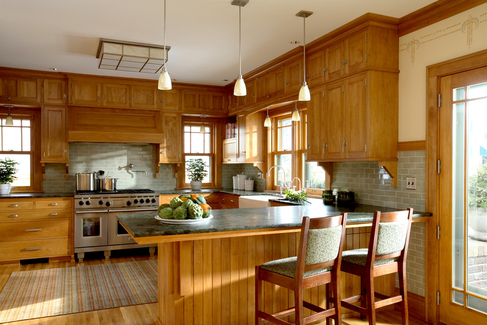 Inspiration for a traditional u-shaped eat-in kitchen in Minneapolis with a farmhouse sink, recessed-panel cabinets, medium wood cabinets, green splashback, subway tile splashback, stainless steel appliances, medium hardwood floors and a peninsula.