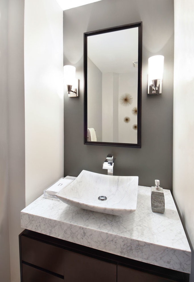 Inspiration for a small modern powder room in Atlanta with flat-panel cabinets, grey walls, a vessel sink, marble benchtops, dark wood cabinets, a one-piece toilet, gray tile, cement tile, medium hardwood floors and white benchtops.