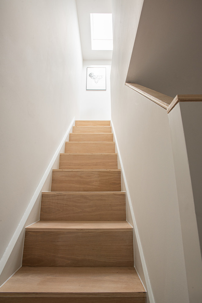Photo of a medium sized scandi wood u-shaped wood railing staircase in London with wood risers.