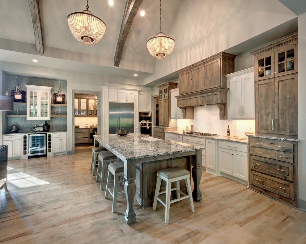 Photo of a country l-shaped kitchen in Kansas City with a farmhouse sink, recessed-panel cabinets, medium wood cabinets, white splashback, window splashback, stainless steel appliances, light hardwood floors, with island, beige floor and grey benchtop.