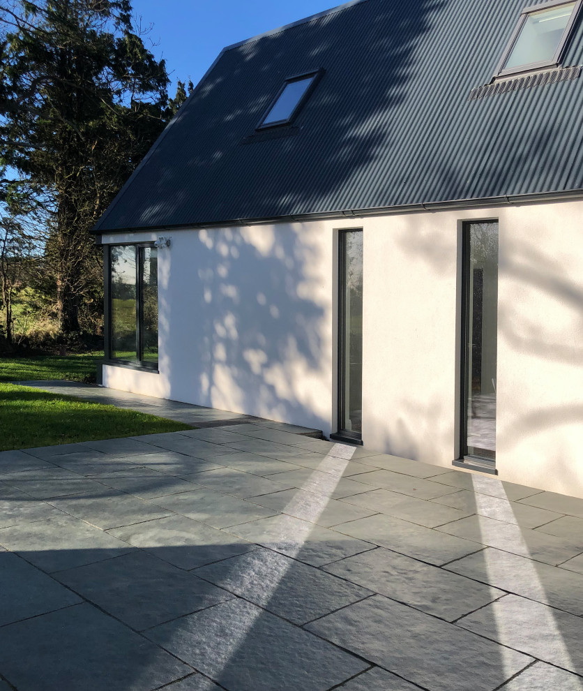 Inspiration for a medium sized and white modern two floor detached house in Dublin with metal cladding, a pitched roof, a metal roof and a grey roof.