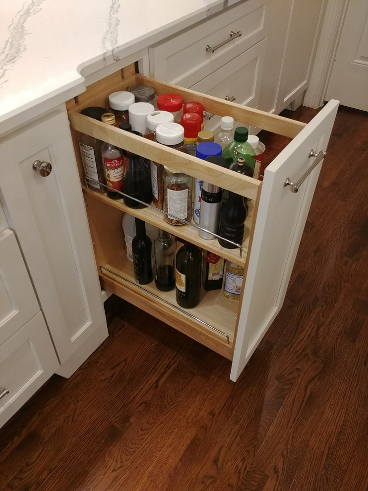 Large transitional single-wall dark wood floor and brown floor enclosed kitchen photo in Nashville with a farmhouse sink, recessed-panel cabinets, white cabinets, quartzite countertops, white backsplash, subway tile backsplash, stainless steel appliances, an island and white countertops