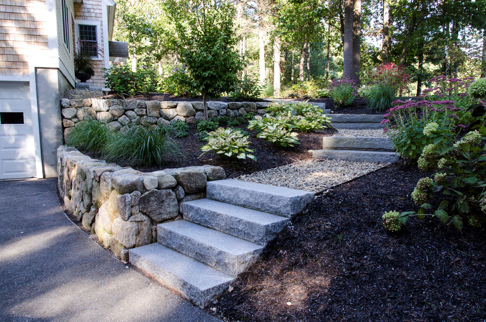 This is an example of a mid-sized transitional front yard partial sun garden in Boston with a retaining wall and gravel.