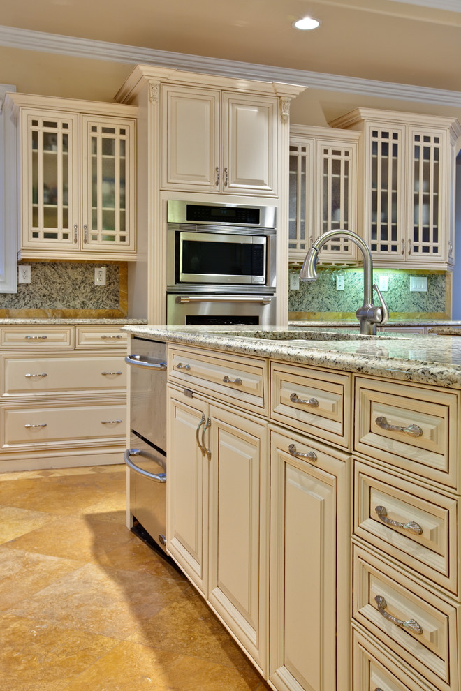 This is an example of an expansive traditional l-shaped eat-in kitchen in Atlanta with raised-panel cabinets, beige cabinets, stainless steel appliances, an undermount sink, granite benchtops, multi-coloured splashback, granite splashback, travertine floors, with island, orange floor and beige benchtop.