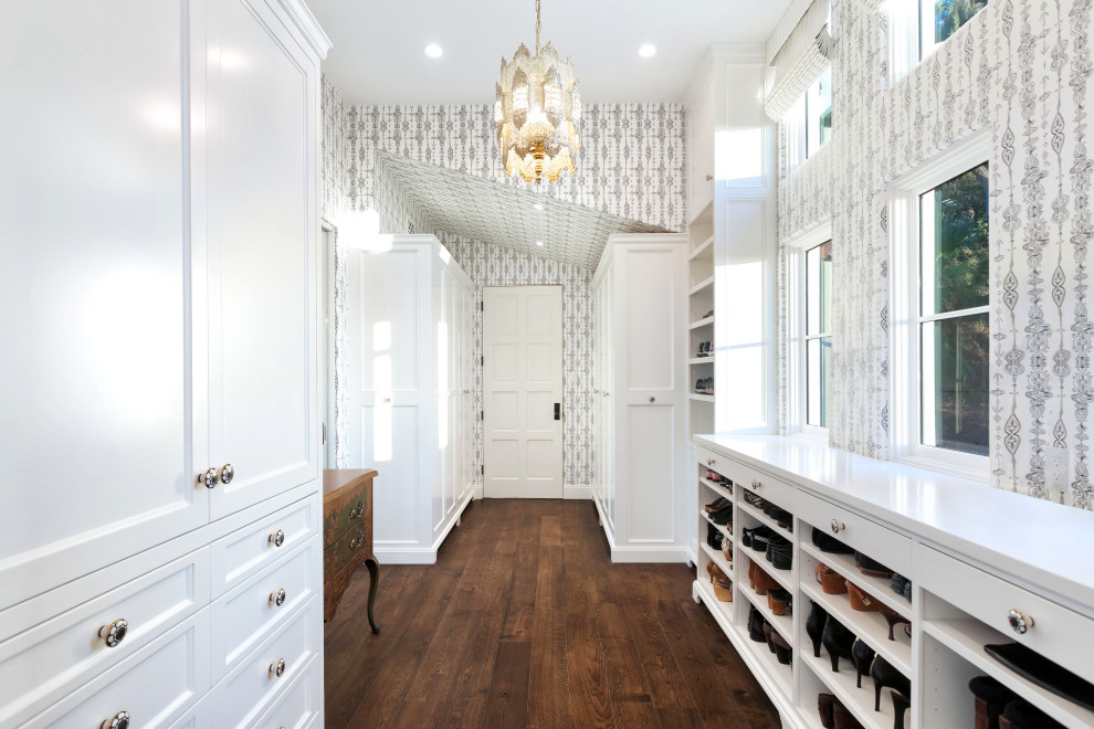 Mid-sized mediterranean women's walk-in wardrobe in Los Angeles with flat-panel cabinets, white cabinets, dark hardwood floors and brown floor.