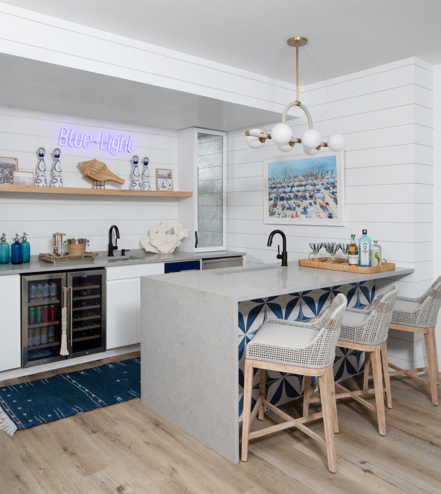 Design ideas for an expansive beach style galley breakfast bar in New York with a submerged sink, flat-panel cabinets, white cabinets, engineered stone countertops, blue splashback, stone tiled splashback, vinyl flooring, brown floors and grey worktops.