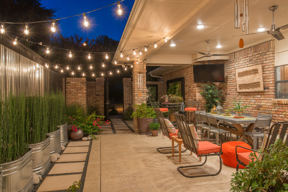 This is an example of an eclectic side yard patio in Dallas with a container garden, stamped concrete and a roof extension.