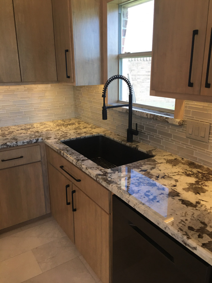 This is an example of a mid-sized transitional u-shaped eat-in kitchen in Houston with an undermount sink, flat-panel cabinets, light wood cabinets, granite benchtops, beige splashback, matchstick tile splashback, black appliances, marble floors, with island, grey floor and multi-coloured benchtop.