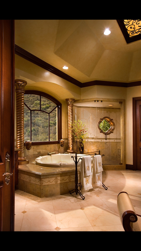 Inspiration for an expansive mediterranean master wet room bathroom in Los Angeles with furniture-like cabinets, dark wood cabinets, a drop-in tub, a one-piece toilet, beige tile, limestone, limestone floors, an undermount sink, granite benchtops, beige floor and a hinged shower door.