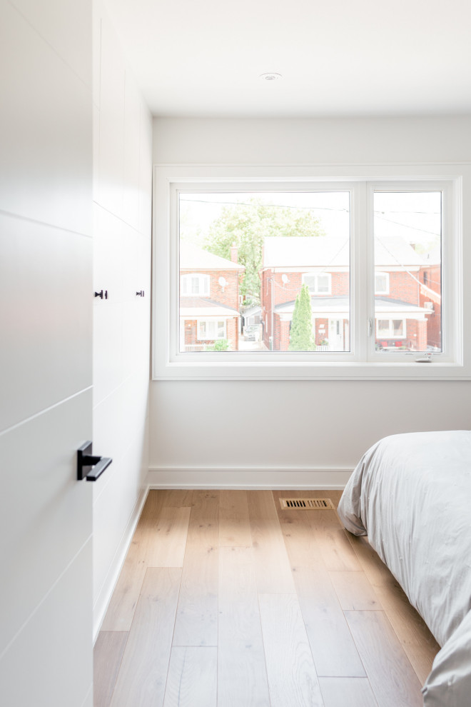 Imagen de habitación de invitados contemporánea de tamaño medio con paredes blancas y suelo de madera clara