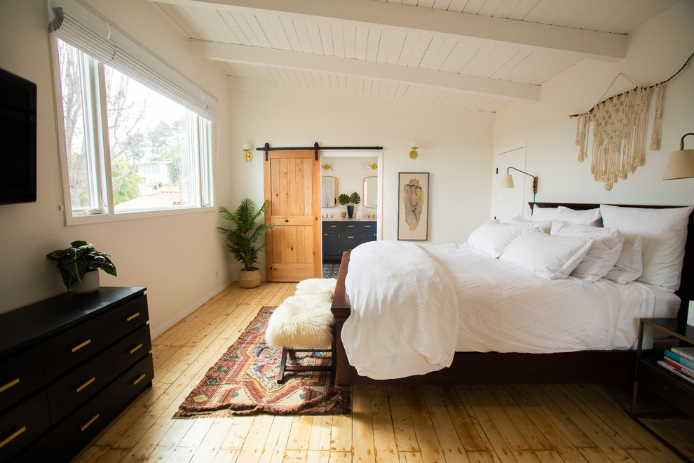 This is an example of a mid-sized midcentury master bedroom in Los Angeles with white walls, light hardwood floors, beige floor and timber.