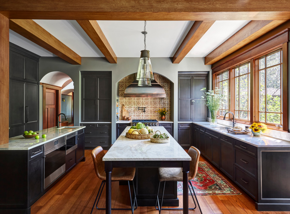 Inspiration for an arts and crafts kitchen in Chicago with recessed-panel cabinets, dark wood cabinets, quartzite benchtops, multi-coloured splashback, terra-cotta splashback, panelled appliances, medium hardwood floors, multiple islands, brown floor, white benchtop and exposed beam.