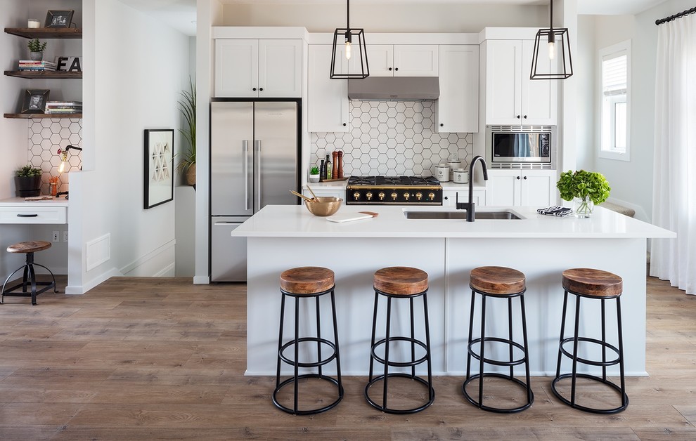 Inspiration for a small country galley open plan kitchen in Vancouver with an undermount sink, shaker cabinets, white cabinets, quartzite benchtops, white splashback, porcelain splashback, stainless steel appliances, laminate floors, with island, white benchtop and brown floor.