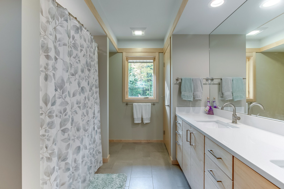 Design ideas for a mid-sized country master bathroom in Other with flat-panel cabinets, light wood cabinets, an alcove tub, a shower/bathtub combo, a one-piece toilet, beige walls, porcelain floors, an undermount sink, engineered quartz benchtops, grey floor, a shower curtain and white benchtops.