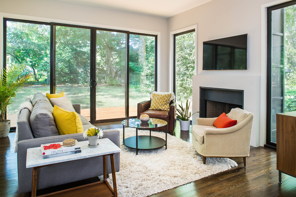 Photo of a mid-sized contemporary open concept living room in Atlanta with grey walls, dark hardwood floors, a standard fireplace, a concrete fireplace surround and a wall-mounted tv.