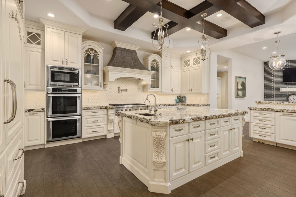 Inspiration for a traditional u-shaped kitchen in Salt Lake City with raised-panel cabinets, beige cabinets, beige splashback, stainless steel appliances, dark hardwood floors, with island, brown floor and multi-coloured benchtop.