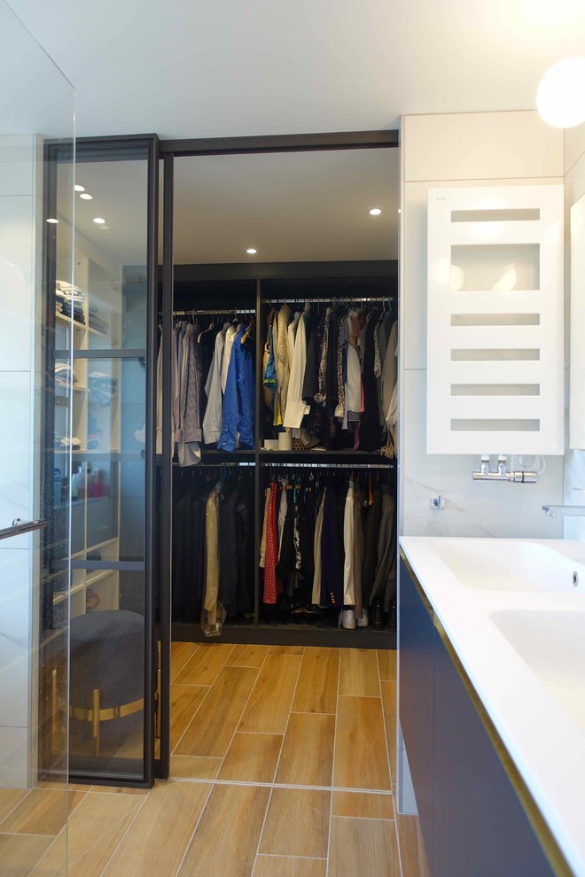 Inspiration for a small contemporary gender-neutral walk-in wardrobe in Paris with open cabinets, black cabinets, light hardwood floors and brown floor.