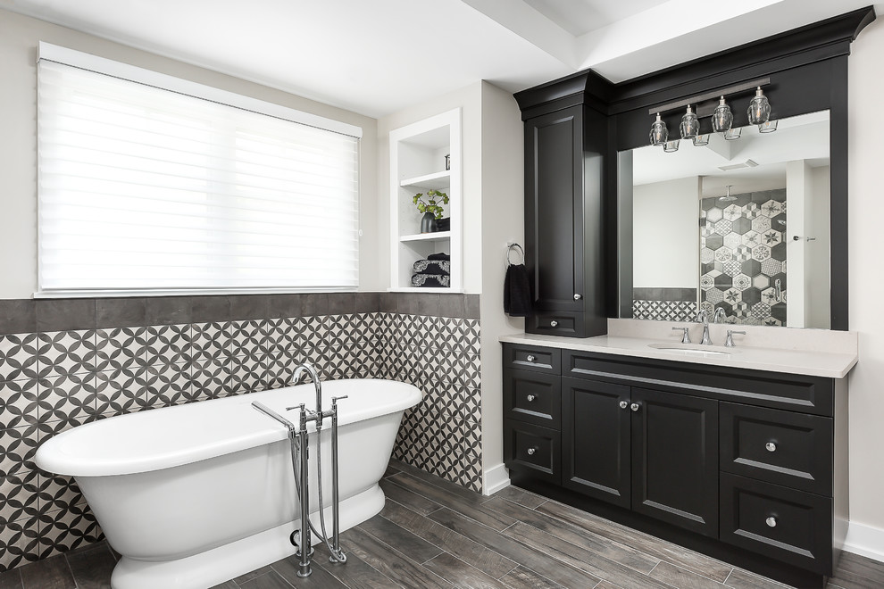 Large transitional master bathroom in Chicago with shaker cabinets, black cabinets, a freestanding tub, black and white tile, mosaic tile, grey walls, ceramic floors, an undermount sink, engineered quartz benchtops, brown floor, white benchtops, a corner shower and a hinged shower door.