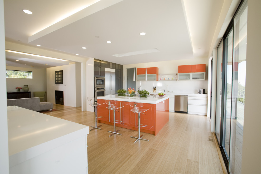 Design ideas for a mid-sized contemporary galley eat-in kitchen in San Francisco with flat-panel cabinets, orange cabinets, an integrated sink, white splashback, stainless steel appliances and bamboo floors.