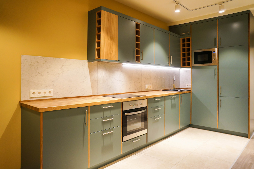 Photo of a mid-sized l-shaped open plan kitchen in Moscow with a drop-in sink, flat-panel cabinets, green cabinets, wood benchtops, green splashback, porcelain splashback, stainless steel appliances, porcelain floors, with island, beige floor and beige benchtop.