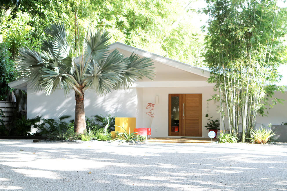 This is an example of a large midcentury one-storey stucco white house exterior in Tampa with a gable roof.