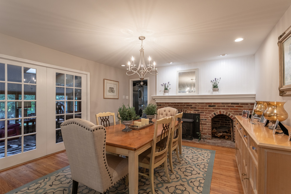 Inspiration for a mid-sized traditional separate dining room in Burlington with beige walls, medium hardwood floors, a ribbon fireplace, a brick fireplace surround, brown floor and decorative wall panelling.