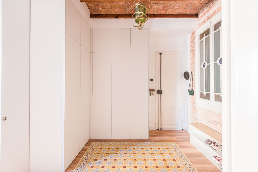 Immagine di una porta d'ingresso classica di medie dimensioni con pareti bianche, pavimento in vinile, una porta singola, una porta bianca, pavimento multicolore, travi a vista e pareti in mattoni