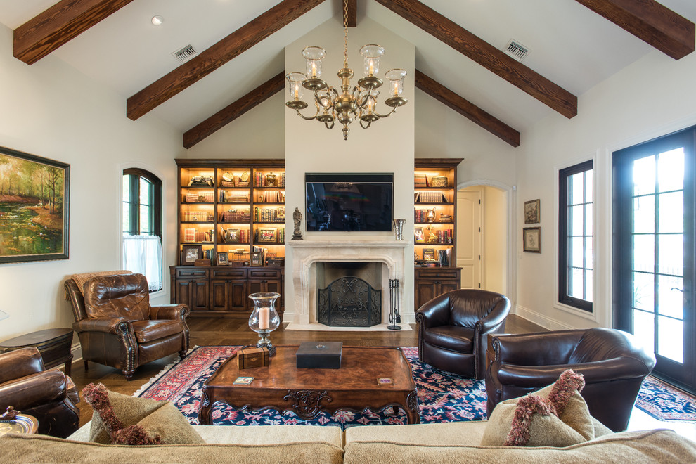 Photo of a traditional family room in Austin with white walls, dark hardwood floors, a standard fireplace and a wall-mounted tv.