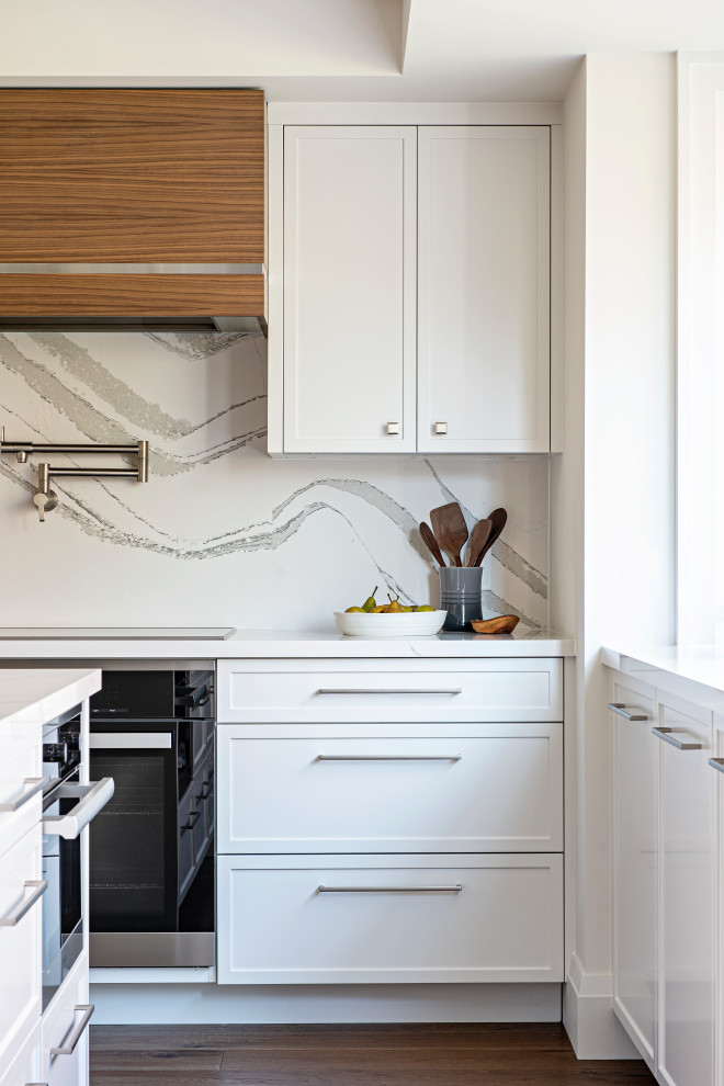 Exempel på ett mellanstort modernt vit vitt kök, med en undermonterad diskho, vita skåp, bänkskiva i kvarts, vitt stänkskydd, rostfria vitvaror, mellanmörkt trägolv och en köksö