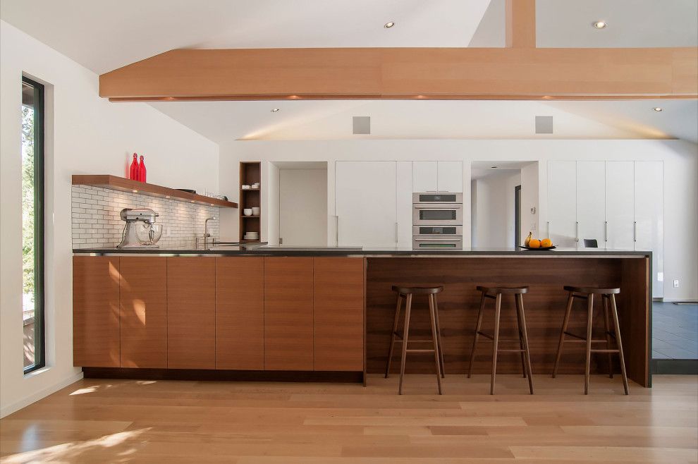This is an example of a large midcentury l-shaped kitchen in Cleveland with a double-bowl sink, flat-panel cabinets, white cabinets, quartz benchtops, yellow splashback, ceramic splashback, stainless steel appliances, marble floors, a peninsula, grey floor, grey benchtop and vaulted.