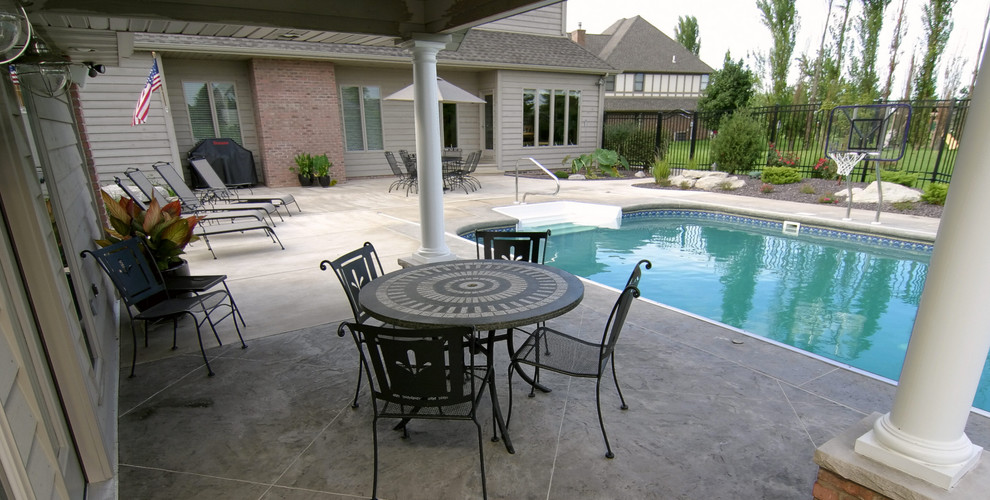 Photo of a large traditional backyard rectangular lap pool in Chicago with a water feature and concrete pavers.