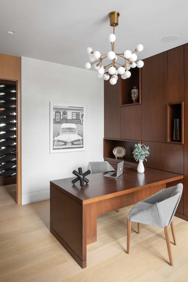 Cette photo montre un bureau moderne de taille moyenne avec un mur marron, parquet clair, un bureau intégré et un sol beige.