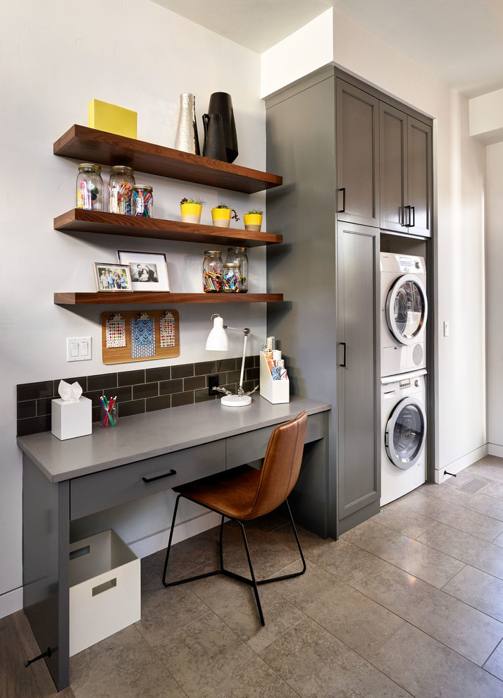 Inspiration for a transitional utility room in Portland with grey cabinets, white walls and a stacked washer and dryer.
