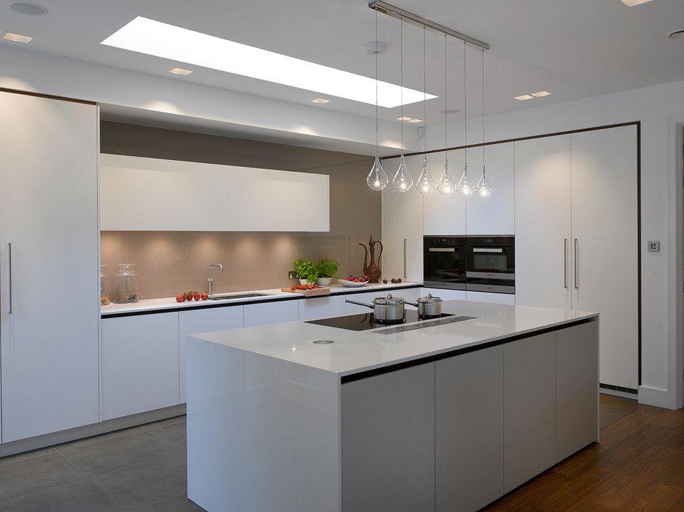 Design ideas for an expansive contemporary open plan kitchen in London with flat-panel cabinets, white cabinets, solid surface benchtops, beige splashback, glass sheet splashback, with island and white benchtop.