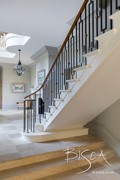 Large traditional staircase in Surrey with metal railing.