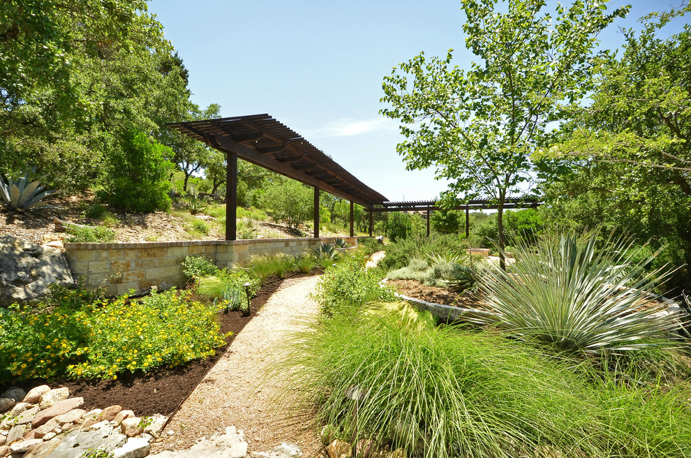Inspiration for a large country sloped garden in Austin with a retaining wall.