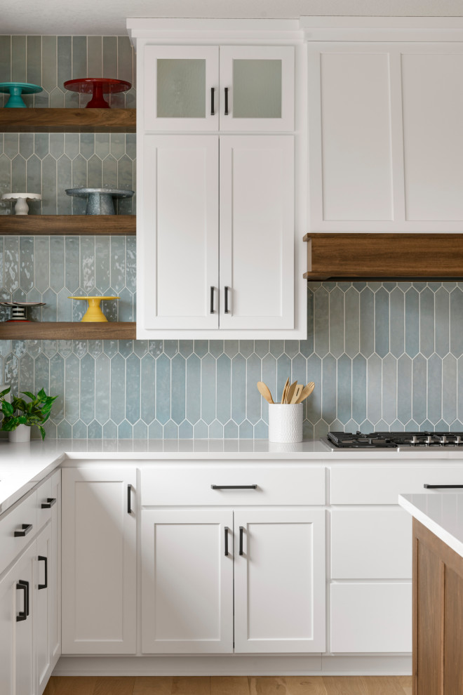 Réalisation d'une cuisine avec des portes de placard blanches, un plan de travail en quartz modifié, une crédence bleue, une crédence en céramique et un plan de travail blanc.