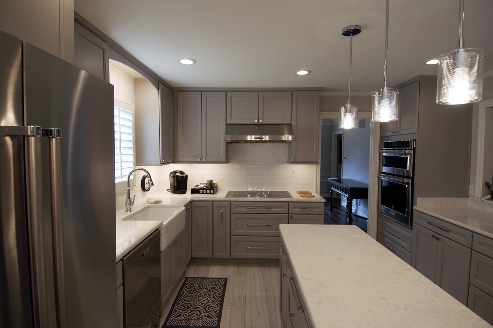 Inspiration for a large transitional u-shaped porcelain tile and beige floor eat-in kitchen remodel with a farmhouse sink, recessed-panel cabinets, gray cabinets, granite countertops, white backsplash, subway tile backsplash, stainless steel appliances, an island and beige countertops