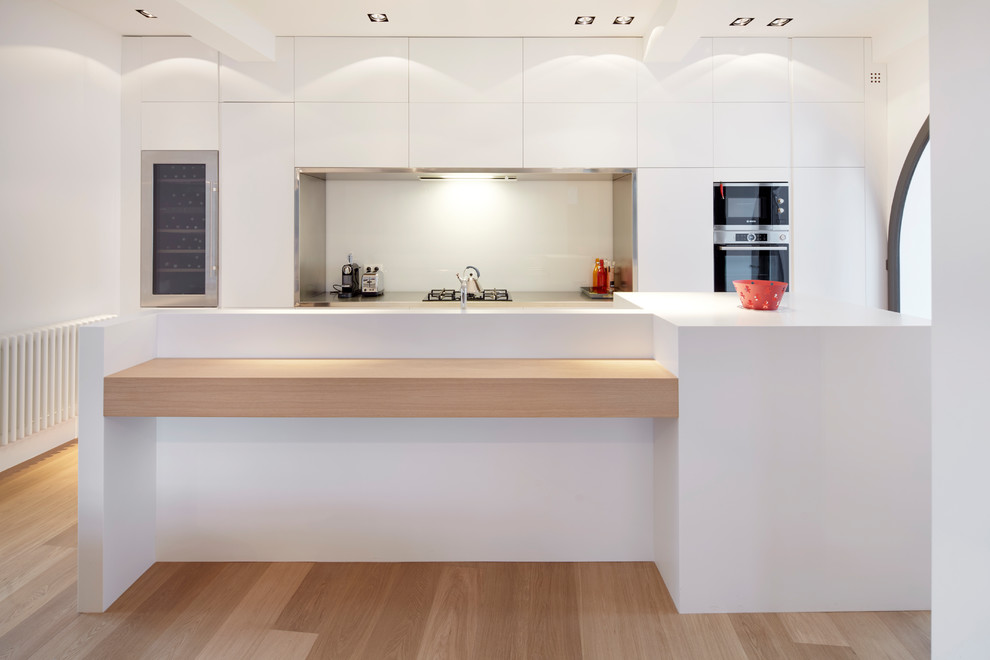 Inspiration for a large contemporary galley open plan kitchen in Other with flat-panel cabinets, white cabinets, white splashback, window splashback and a peninsula.