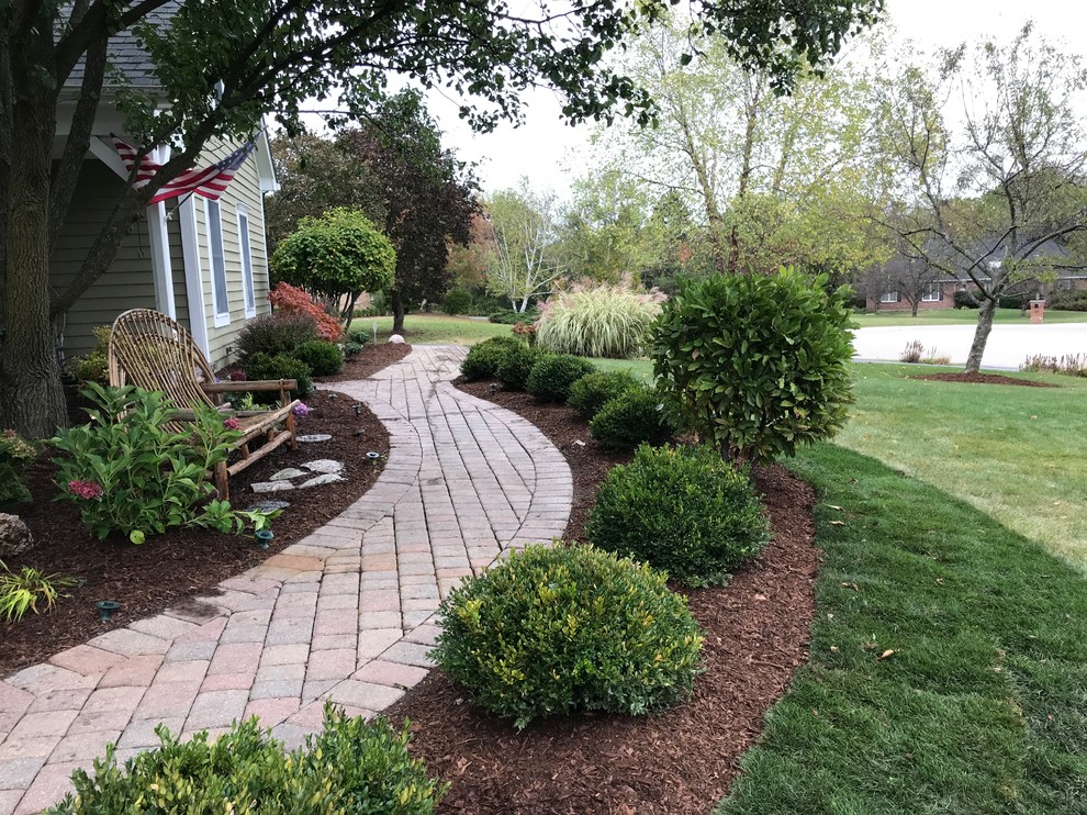 This is an example of a large traditional front yard full sun formal garden for winter in Chicago with a garden path and natural stone pavers.